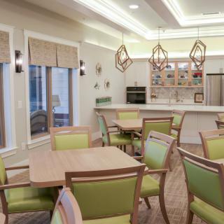 A modern dining area with green-accented chairs, geometric lighting fixtures, and a cozy ambiance.