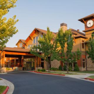 A modern building with a clock tower surrounded by trees.