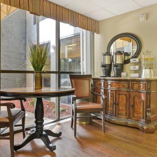 A cozy hotel lobby with a coffee station and seating area near a large window.