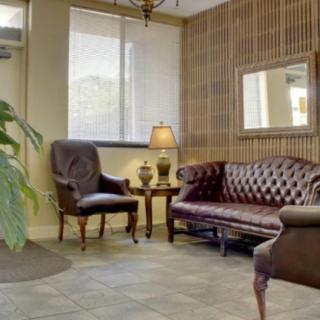 A cozy lobby area with a leather sofa, armchair, and warm lighting.