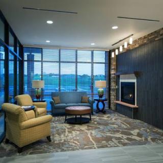 A modern lounge area featuring comfortable seating, a stylish fireplace, and large windows that offer a view outside.