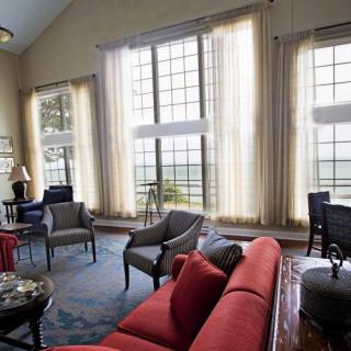 A spacious living room with large windows allowing natural light to fill the space, featuring comfortable seating and elegant decor.