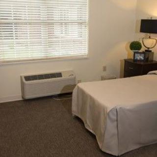 A minimalist bedroom with a single bed, nightstand, and window.