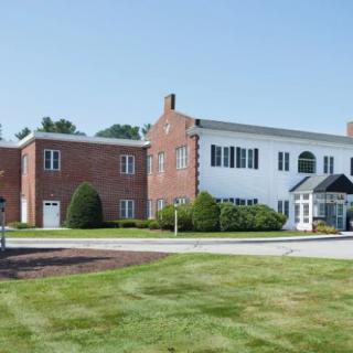A brick building with large windows and a landscaped lawn on a clear day.