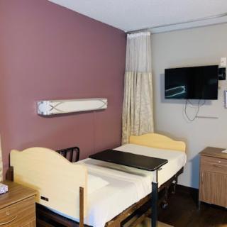 A clean and organized hospital room equipped with a bed and television.