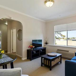 A cozy living room with a television, coffee table, and large window providing ample natural light.
