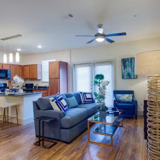 A modern living room with an open floor plan, featuring a sofa, kitchen area, and stylish decor.