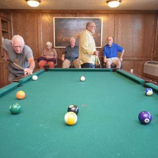 A group of men enjoying a game of billiards in a cozy game room.