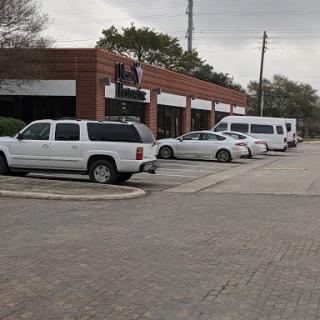 A view of a commercial building with several white vehicles parked outside on a cloudy day.