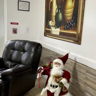 A festive corner featuring a Santa Claus figure, an elegant painting, and a cozy chair.