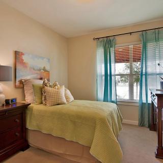 A cozy bedroom with a well-decorated bed, teal curtains, and a window view.