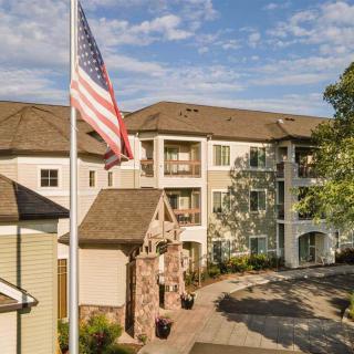 A residential apartment complex with an American flag in the foreground on a sunny day.