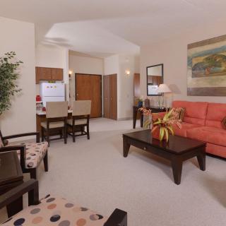 A modern living room with an open layout, featuring a red sofa, chairs, coffee table, and dining area.
