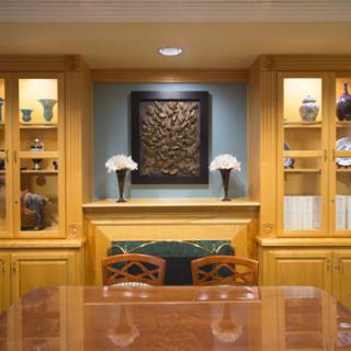 A cozy dining room with wooden cabinets and display shelves featuring decorative vases and artwork.