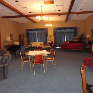 A spacious living room with a variety of seating options, including sofas and chairs around a table, set on a carpeted floor.