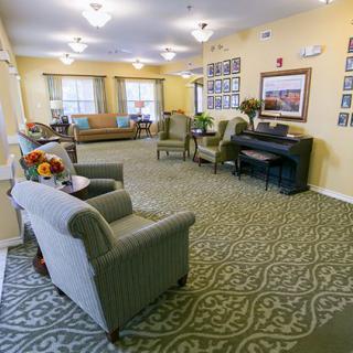 A cozy living area with comfortable seating and a piano, featuring warm lighting and decorative elements.