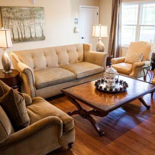 A cozy living room with a sofa, armchair, and a wooden coffee table adorned with decorative items.