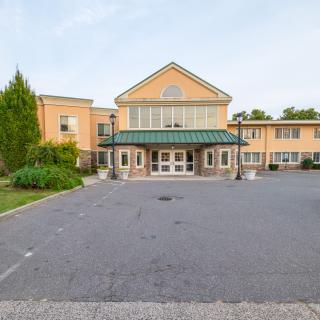 The exterior of a hotel with a parking lot in front.