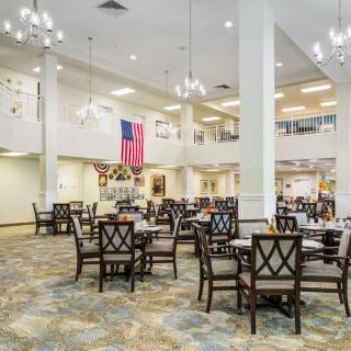 A spacious dining area with tables, chairs, chandeliers, and flags on display.