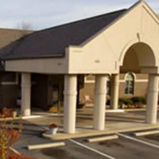 A building entrance with columns and an adjacent parking lot.
