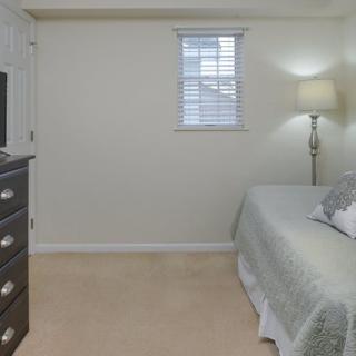 A cozy bedroom with a bed, lamp, and dresser.