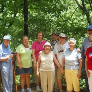 A group of senior citizens enjoying a sunny day outdoors in a lush green setting.