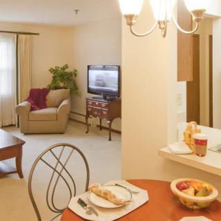 A cozy living and dining area with a comfortable armchair, TV, and a table set for two.