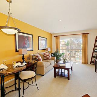 Cozy living room with warm colors, featuring a sofa, dining table, and large windows.