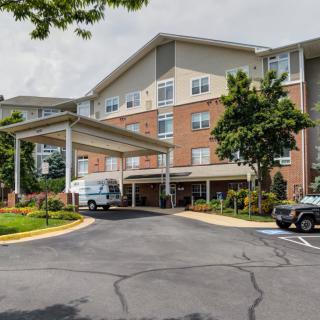 A residential building with a covered entrance and parked vehicles.