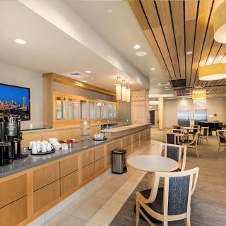 A modern lounge area with a coffee station, tables, and comfortable seating.