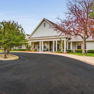 A residential building with a driveway and surrounding trees.