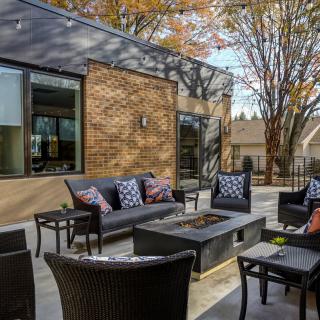 A modern outdoor patio with comfortable seating and a brick exterior.