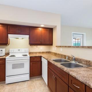 A modern kitchen with dark wood cabinets, a white stove, and a double sink.