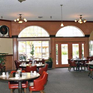 A cozy restaurant dining area with tables and chairs, large windows, and warm lighting.