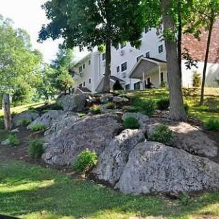A house with a rock garden and trees on a sloped hill.