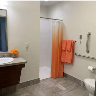 Modern bathroom with accessible facilities and orange accents.