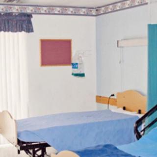 A tidy hospital room with a bed and medical equipment.