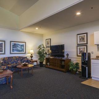 A cozy living room with a sofa, television, artwork on the walls, and indoor plants for decoration.