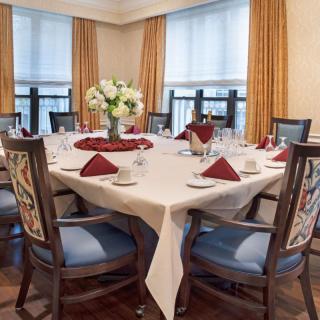 A well-set dining table with elegant decor, featuring a floral centerpiece and neatly arranged napkins.