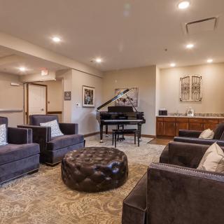 A stylish and comfortable living room with a grand piano, surrounded by plush seating and tasteful decor.