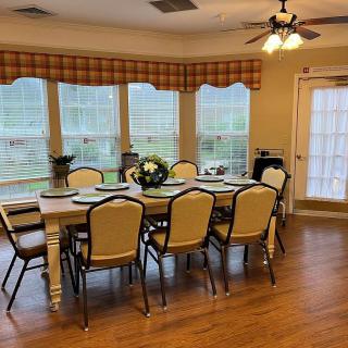 A cozy dining room with a table set for a meal, surrounded by chairs and large windows.