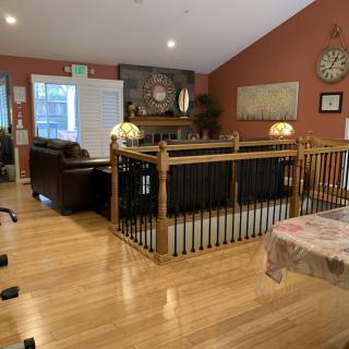 A cozy living room with wooden floors, a couch, and decorated with wall art and a clock.