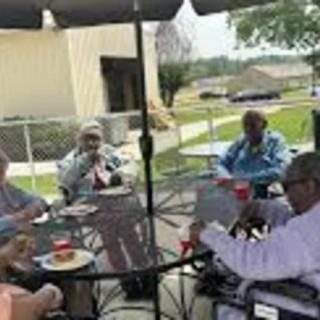 A group of seniors sitting together on a patio, enjoying a conversation.