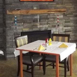 A cozy restaurant dining table set for two, with a rustic brick fireplace in the background.
