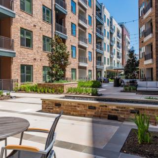 A modern apartment complex with outdoor seating and landscaped areas.