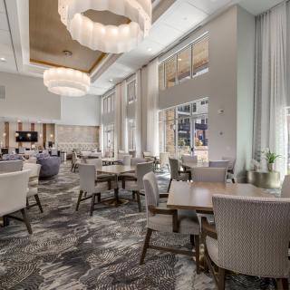 A modern and elegant restaurant interior featuring chic furniture and large chandeliers.
