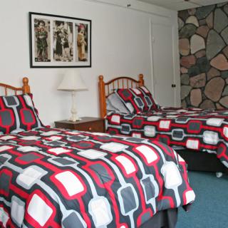 A cozy bedroom with two twin beds featuring patterned bedding and a stone accent wall.