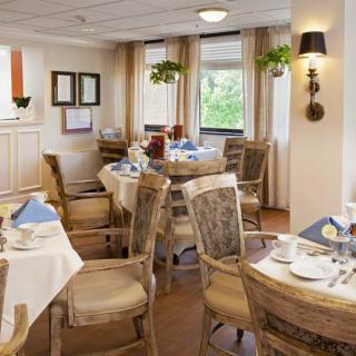 A cozy dining area with elegantly set tables and comfortable chairs by the windows.