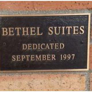 A dedication plaque for Bethel Suites, dated September 1997, mounted on a brick wall.