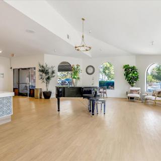 A bright and spacious lobby featuring a modern design with a piano and lush greenery.